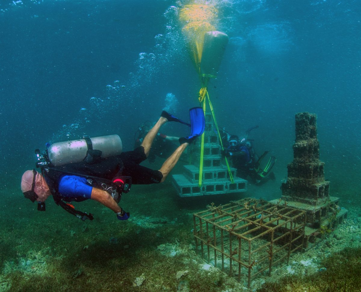 Phil Saye swims in SCUBA gear in front of underwater pyramids in the Grenada Artificial Reef Project.