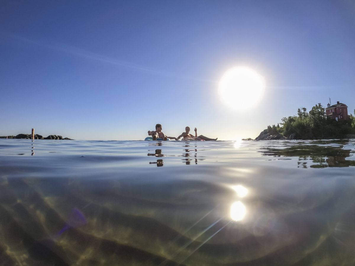 Underwater views at a Lake Superior beach in Marquette, Michigan. Two people float on tubes under the sun.