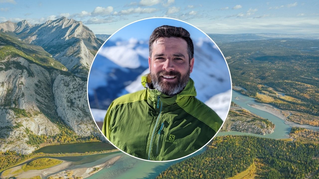 Headshot of a smiling, light-skinned man wearing a ski jacket is set atop an aerial shot of mountains near Jasper, Alberta.