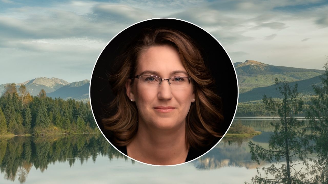 A headshot of Amy Thacker placed atop a background image of a lake and mountains taken in the Cariboo Chilcotin Coast.