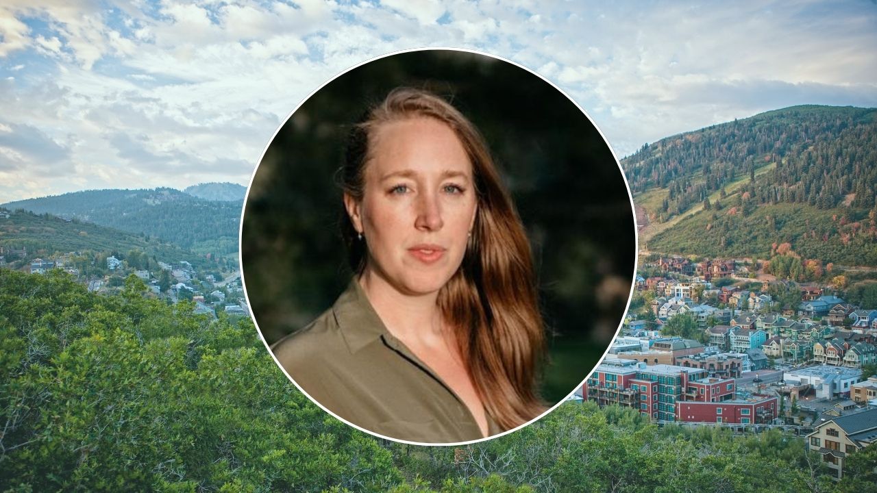 A white woman with red hair faces the camera in a headshot photo. The background image shows a wide valley where Park City is located.