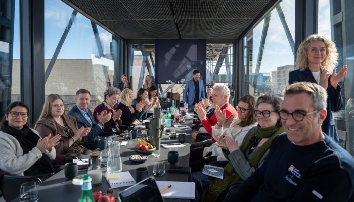 A room full of meeting attendees applauds.
