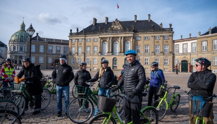Attendees stand with bicycles in a Copenhagen public square.