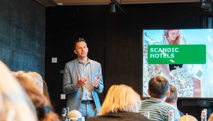 A man from Scandic Hotels speaks to attendees.