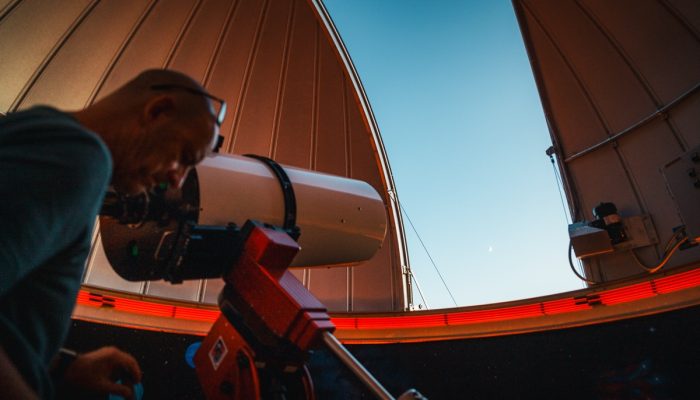 A man bends down to look into a telescope at an observatory.