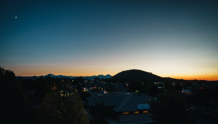 A crescent moon floats in the clear night sky above Bend, Oregon.